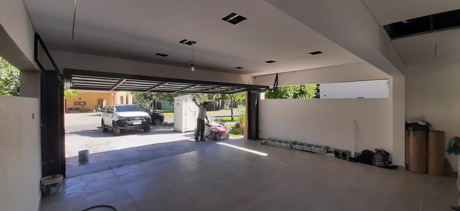 Entrada de garage moderna con puerta levadiza abierta y auto — proyecto Ampliación Residencial Barrio Terravista, por ODF Arquitectura & Obra, en Gral. Rodríguez